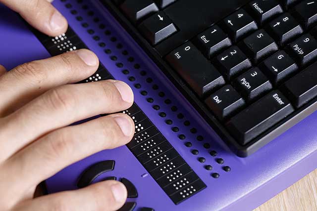 A blind person using a brail keyboard to illustrate the concept of ADA website compliance