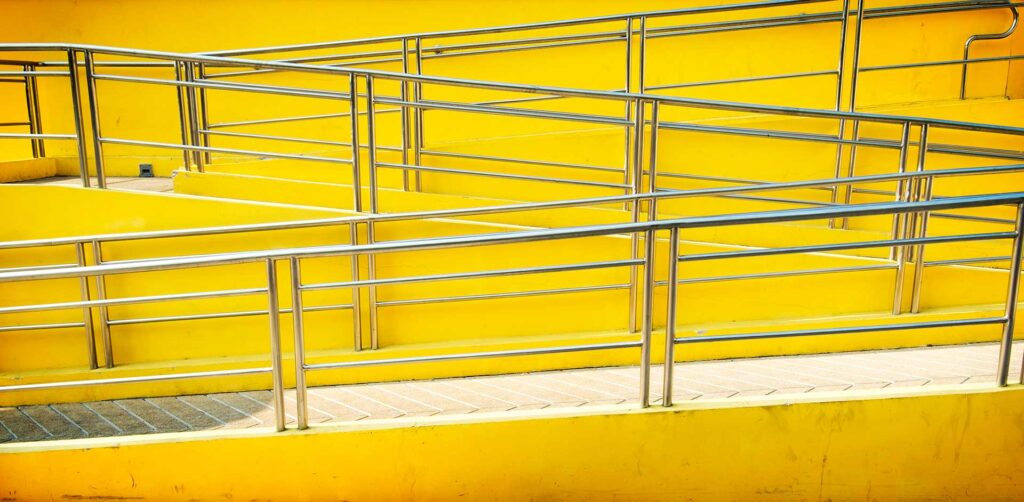 Wheelchair ramp ascending, yellow background, illustrating ADA compliant web design services